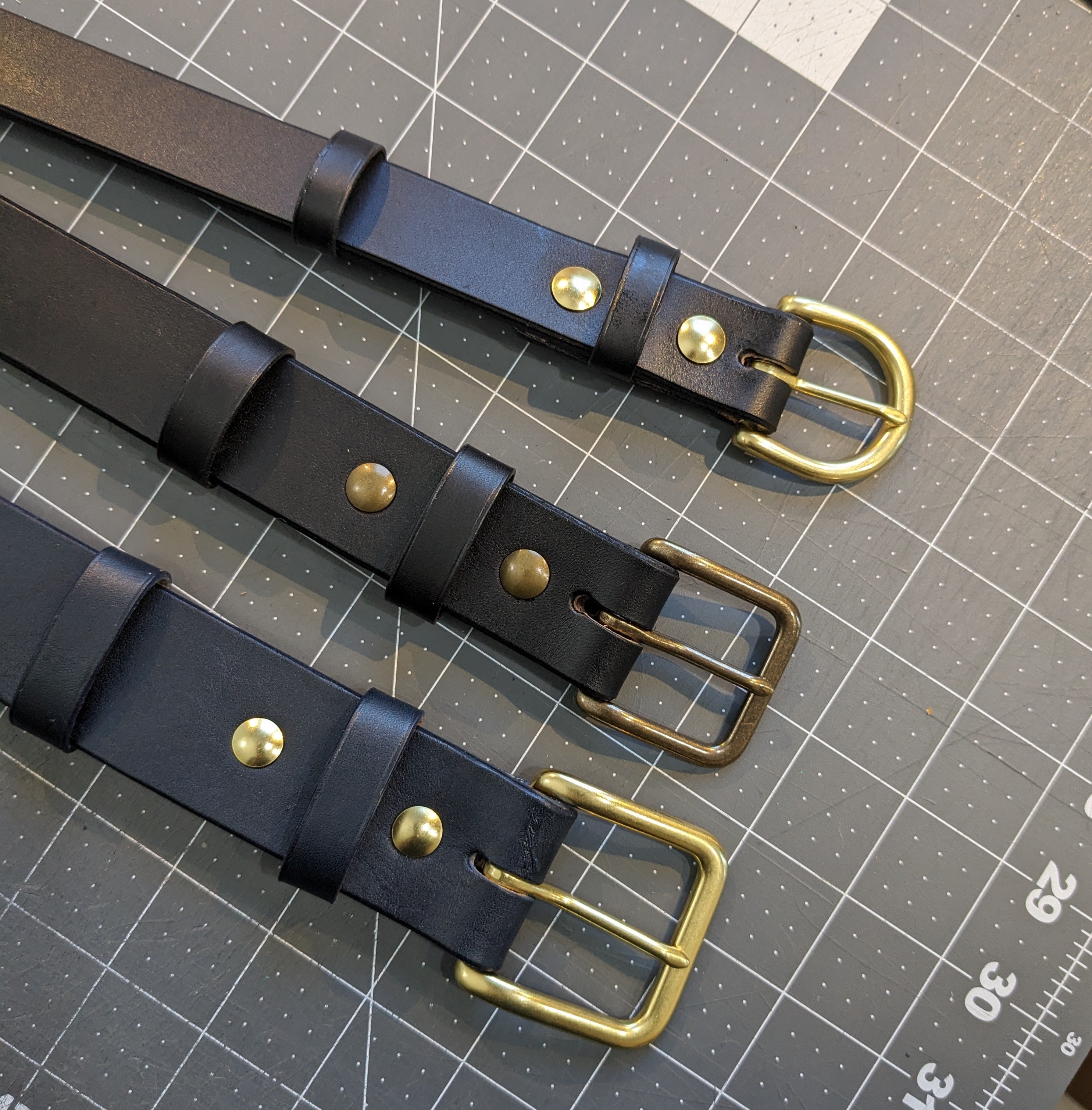 3 Handcrafted Black Leather Belts with various width and types of brass buckles.